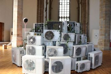 Unheimliche Verschiebungen. Foto: Erik Benger Ein Berg aus Klimaanlagen im Innenraum einer Kirche.