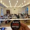 "Black Lives Matter" Plakette und Teilnehmende der Tagung