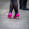 Eine Frau steht mit ihren pinken Absatzschuhen in der Stadt. Foto: Unsplash