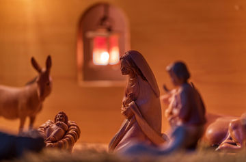 Weihnachtskrippe: Maria und Jesuskind in der Krippe im Vordergrund, im Hintergrund unscharf Esel, Engel