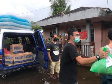 Zwei Männer stehen vor einem Lieferwagen mit Kartons und verteilen Hilfsgüter.